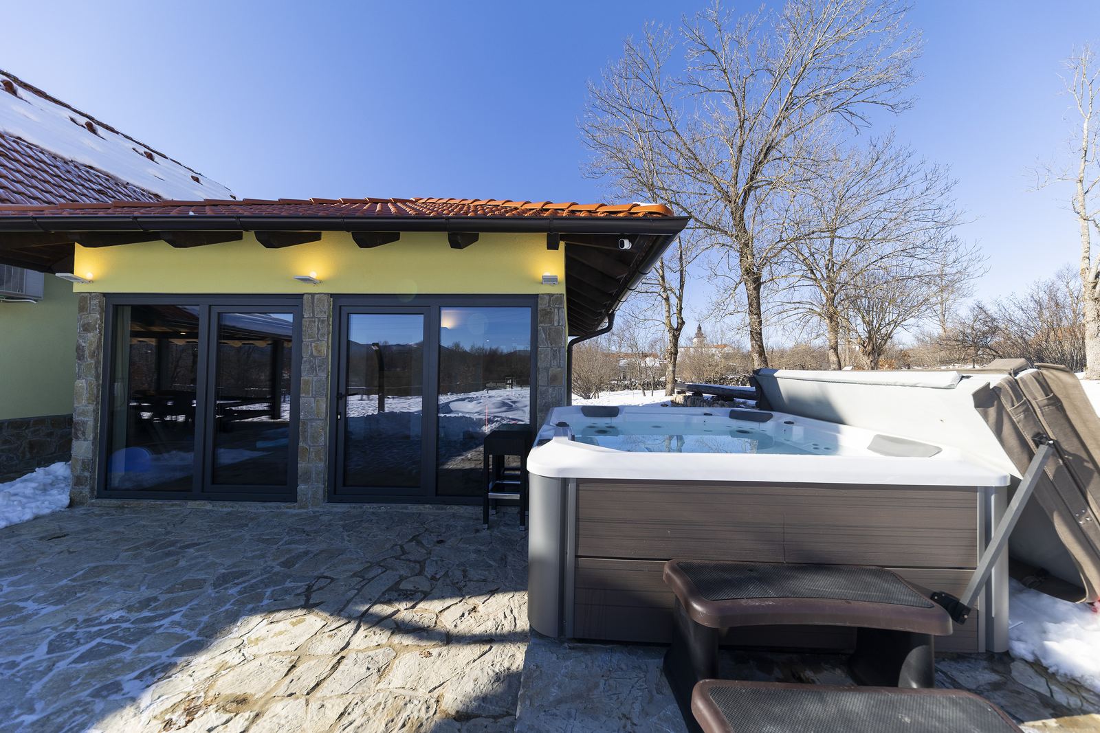 Vasca idromassaggio davanti all'edificio spa vetrato, d'inverno