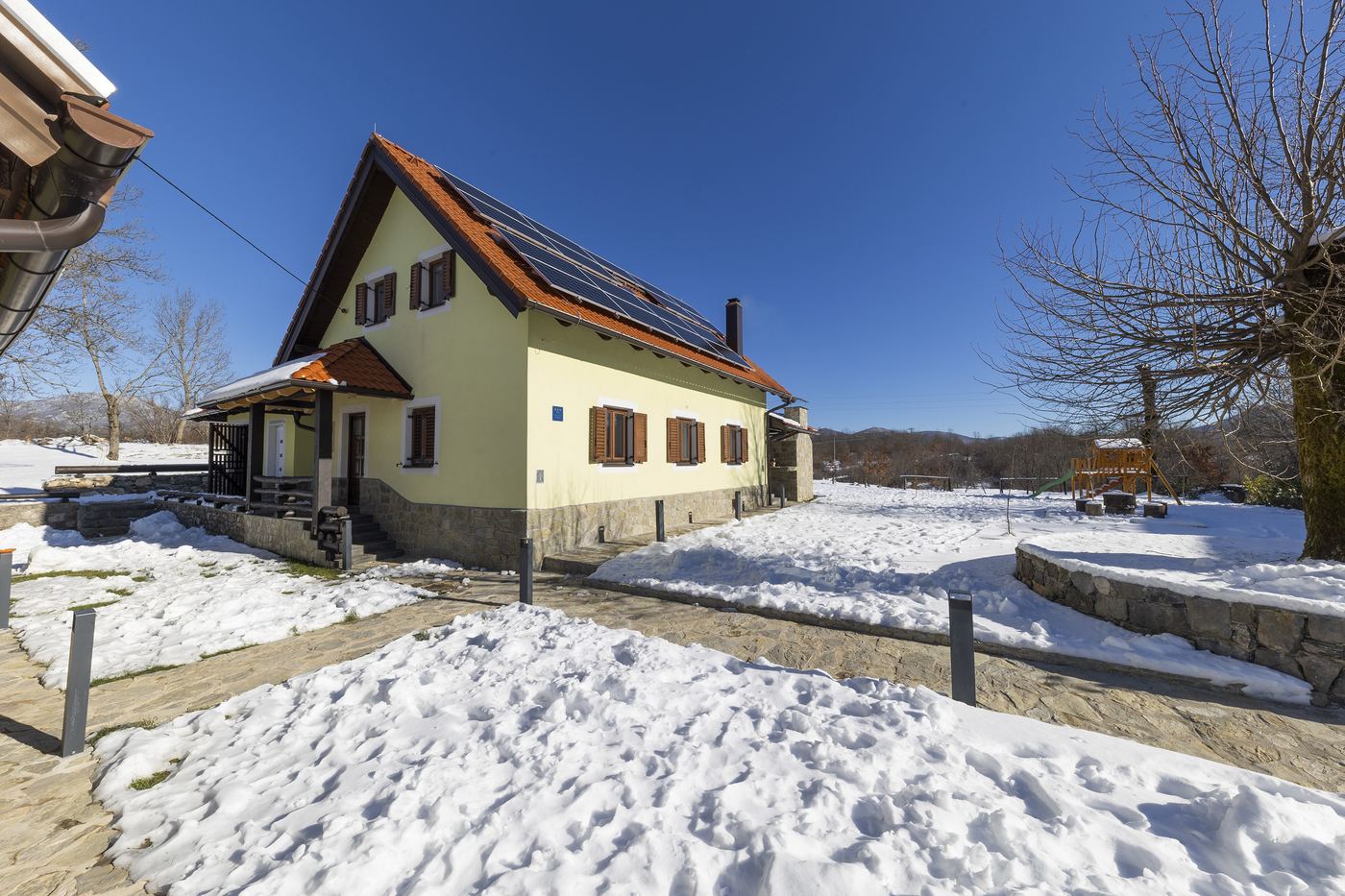 Kuća okružena snijegom za sunčanog dana